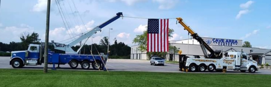 two crane tow trucks holding American flag
