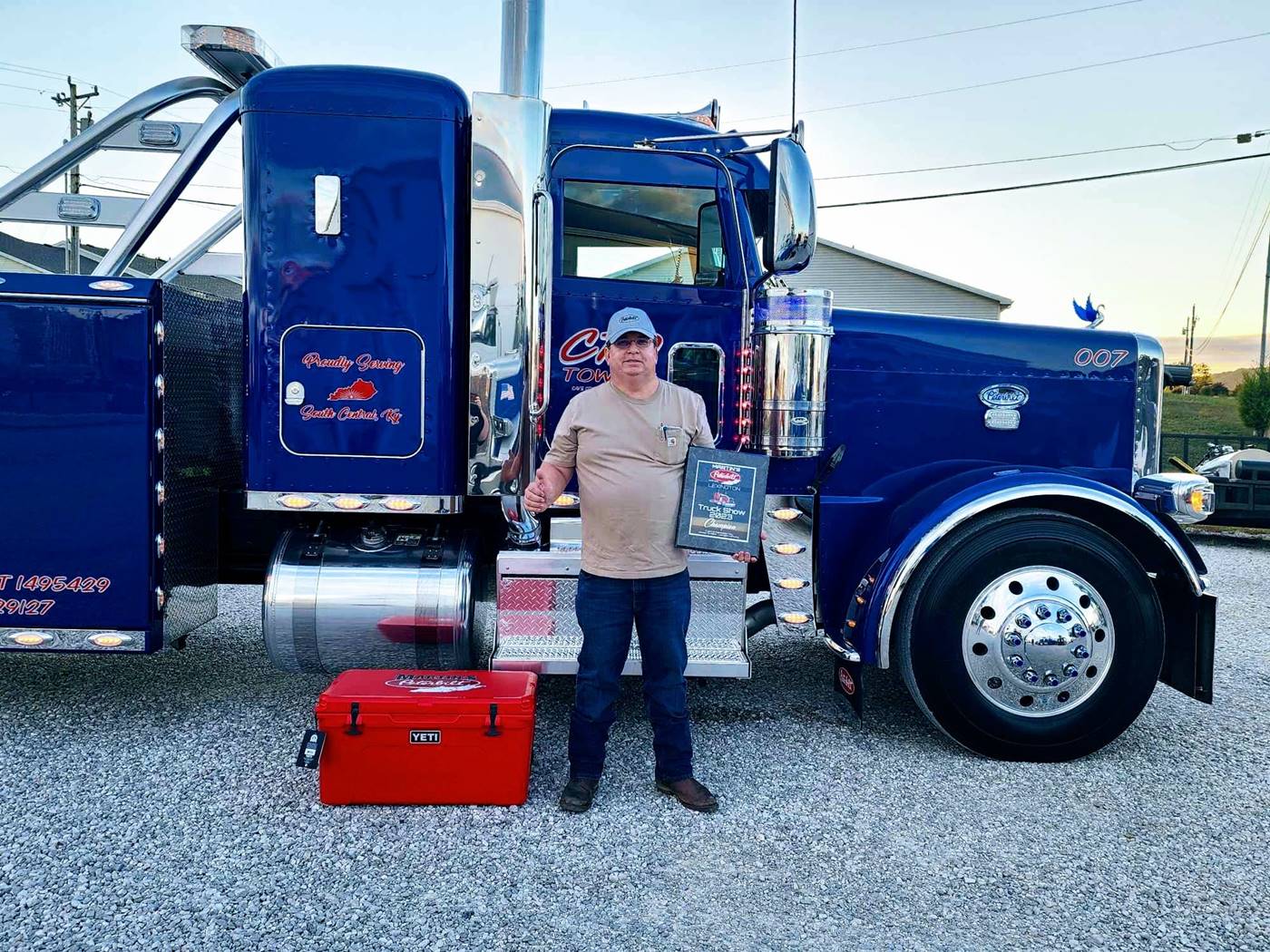 owner with awards in front of tow truck