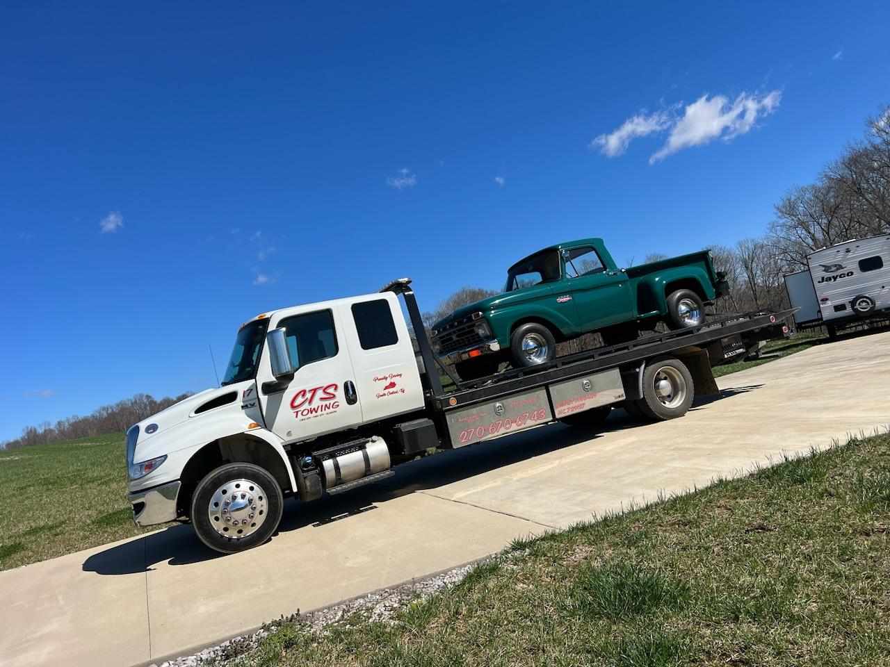 light towing truck hauling antique green truck
